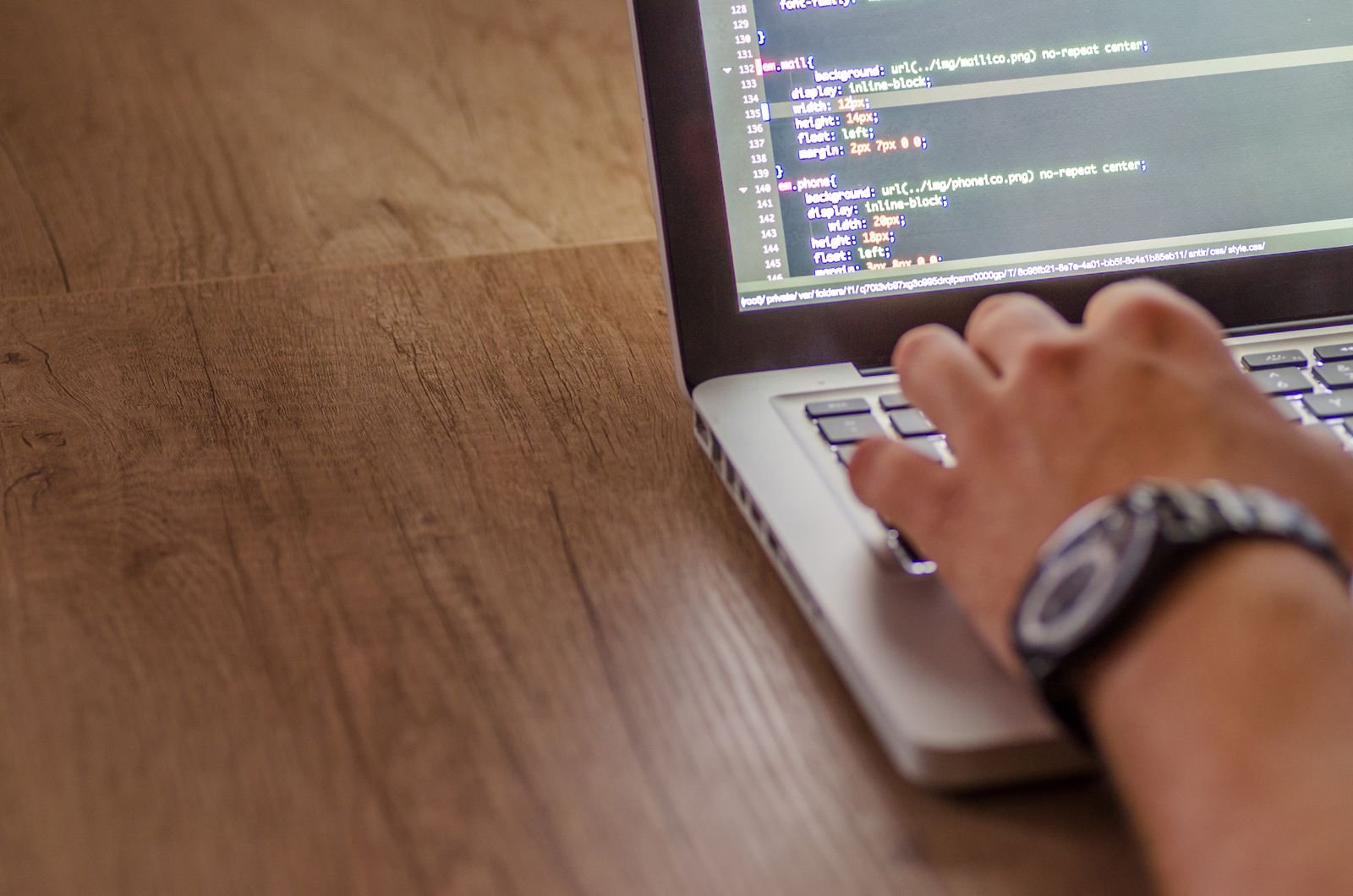 Close-up of hands typing code on a laptop at a design agency