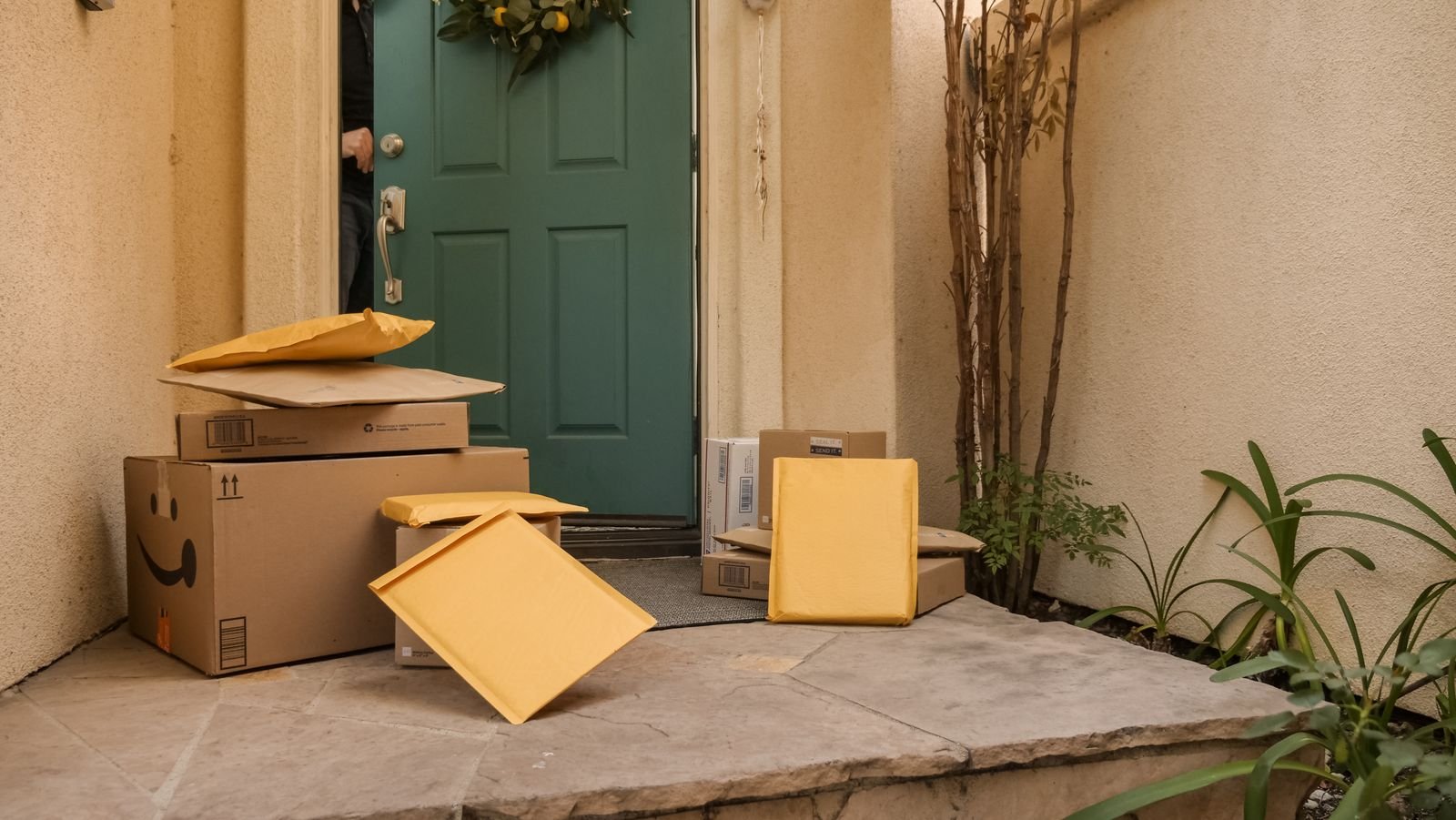 Multiple e-commerce delivery packages stacked at a front door
